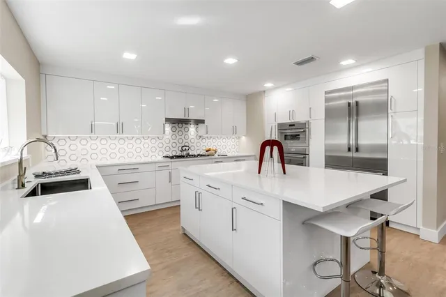 a kitchen with center island with sink and a large window