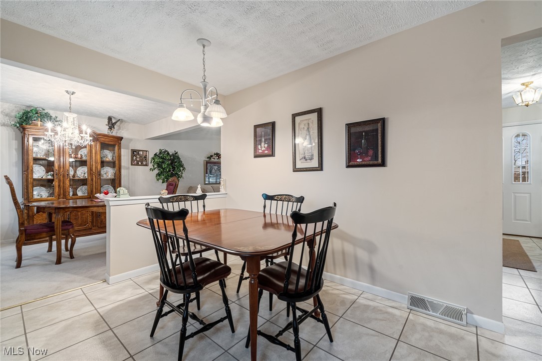7353 Ames Road Cleveland, OH 44129 - Photo 19 of 45 Dining space with light tile patterned floors, a notable chandelier, a textured ceiling, and visible vents