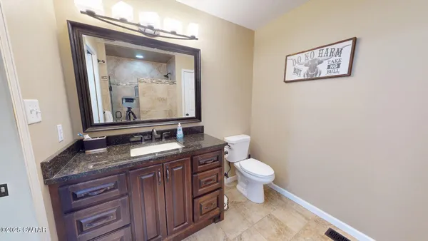 a bathroom with a granite countertop toilet a sink and mirror
