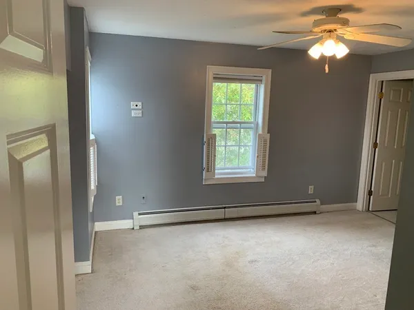 an empty room with windows and fan