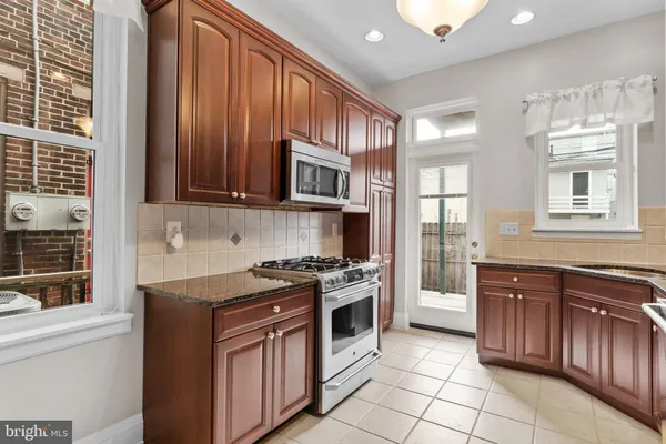 a kitchen with stainless steel appliances granite countertop a stove a sink and a microwave