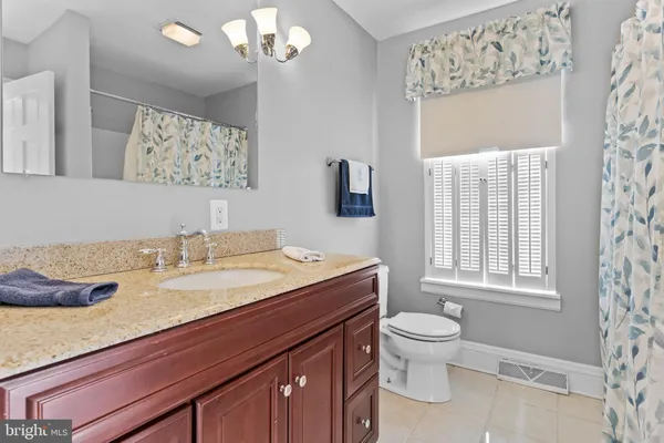 a bathroom with a granite countertop toilet sink and mirror