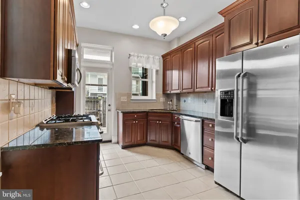 a kitchen with stainless steel appliances granite countertop a refrigerator a stove and a sink