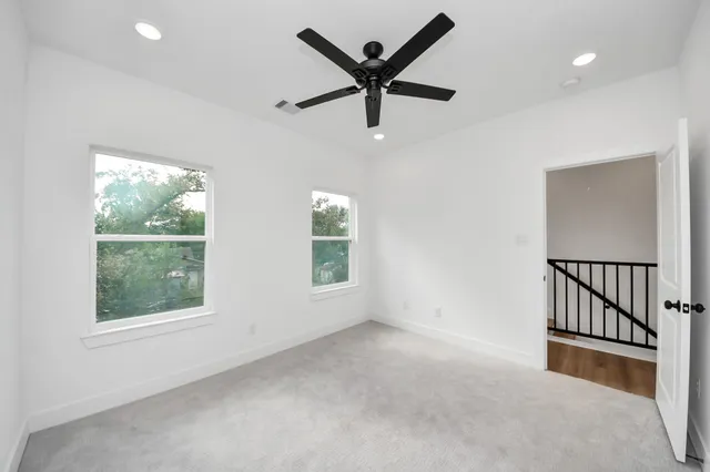an empty room with ceiling fan and windows