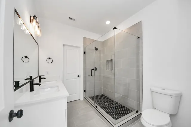 a bathroom with a shower sink mirror and toilet