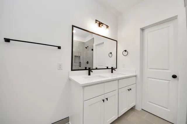 a bathroom with a double vanity sink a mirror and shower
