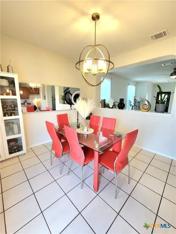 a dining room with red chandelier and kitchen view