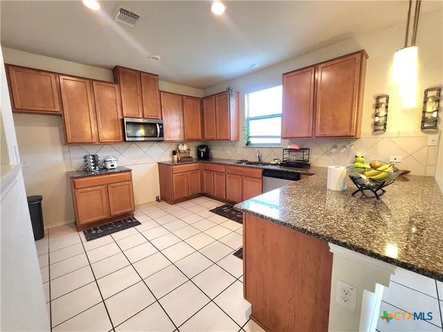 a kitchen with stainless steel appliances granite countertop a sink a stove top oven a counter space and cabinets
