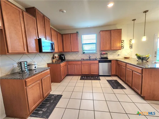 a kitchen with stainless steel appliances a sink a stove a microwave cabinets and a window