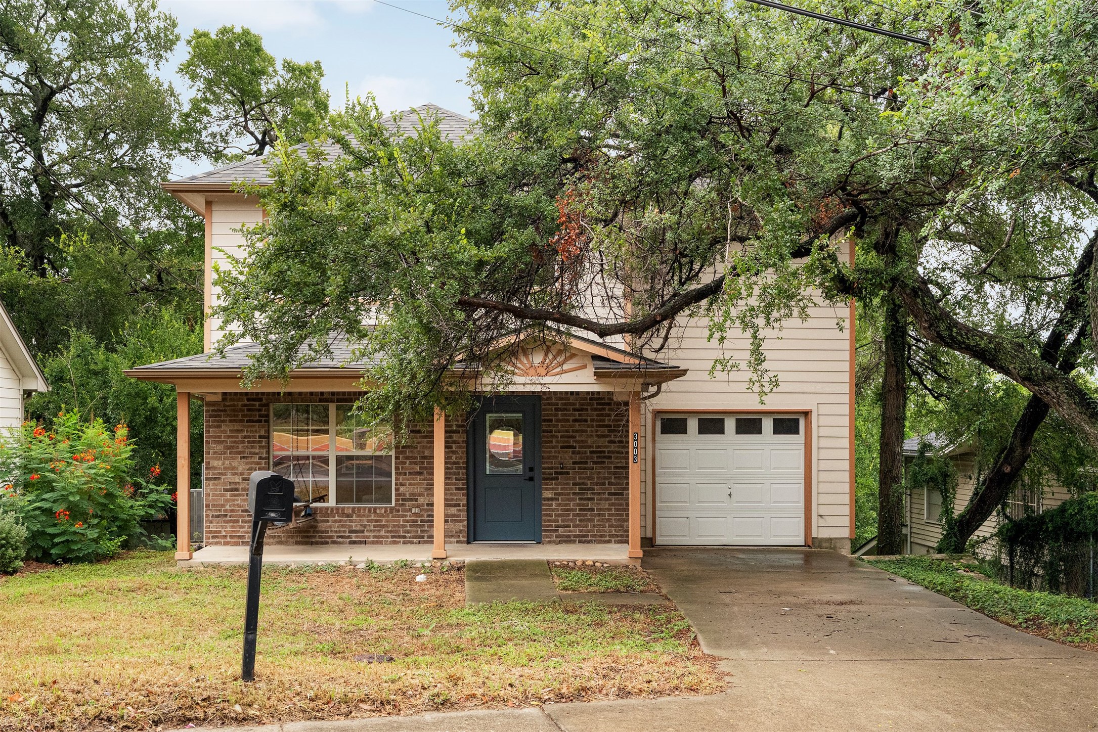 3003 Glen Rae Street Austin, TX 78702 - Photo 2 of 38 An attached one-car garage provides essential off-street parking or extra storage, while the wide front porch offers a welcoming spot to sit and enjoy the relaxed, shaded ambiance of this tree-covered East Austin lot