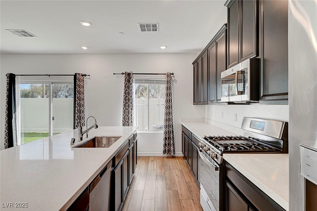 7204 North Decatur Boulevard North Las Vegas, NV 89084 - Photo 22 of 55 Kitchen with light wood-type flooring, light countertops, a sink, and stainless steel appliances