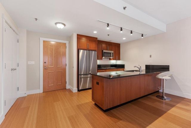 a kitchen with stainless steel appliances granite countertop a refrigerator a sink dishwasher and a stove with wooden floor