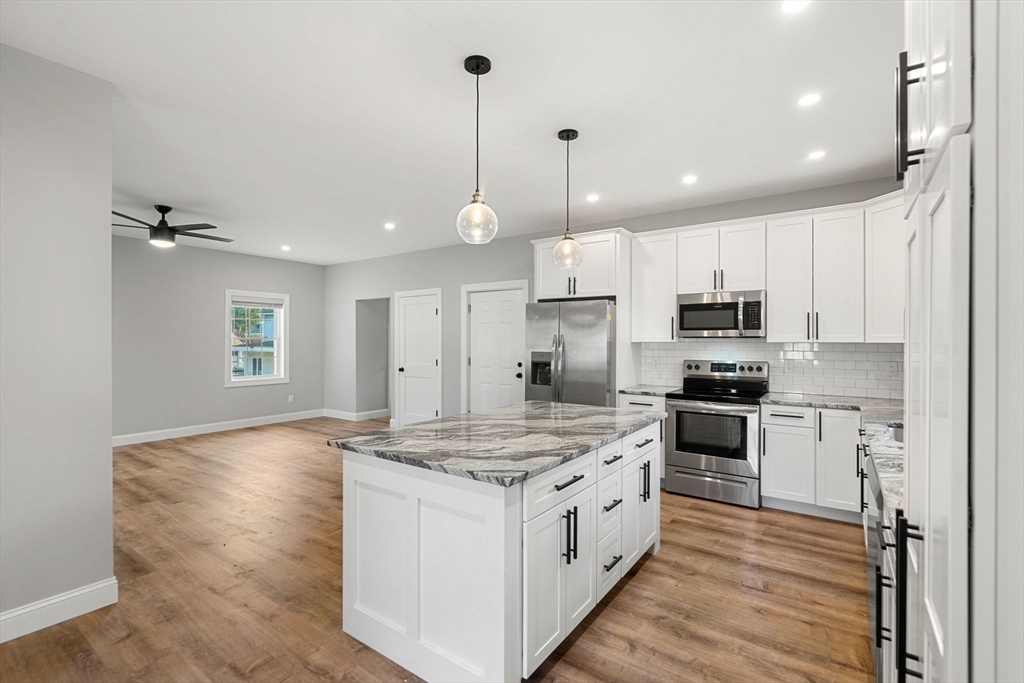 249 Brookside Road Orange, MA 01364 - Photo 11 of 37 a kitchen with kitchen island granite countertop a sink appliances and wooden floor