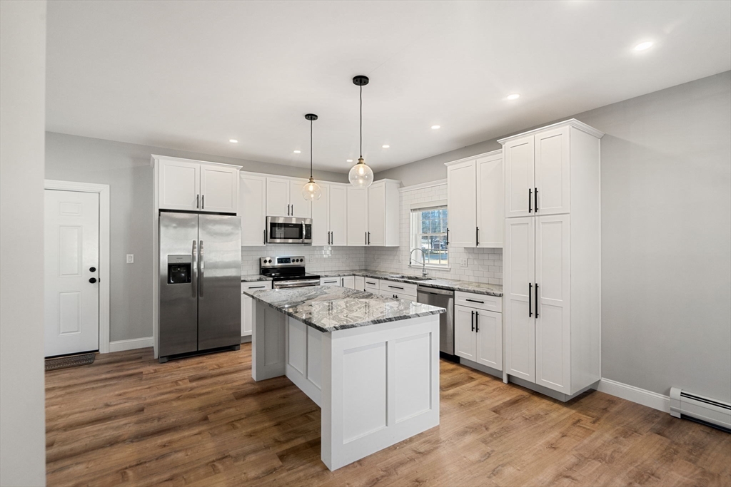 249 Brookside Road Orange, MA 01364 - Photo 6 of 37 a kitchen with stainless steel appliances granite countertop a refrigerator a oven a sink and white cabinets with wooden floor