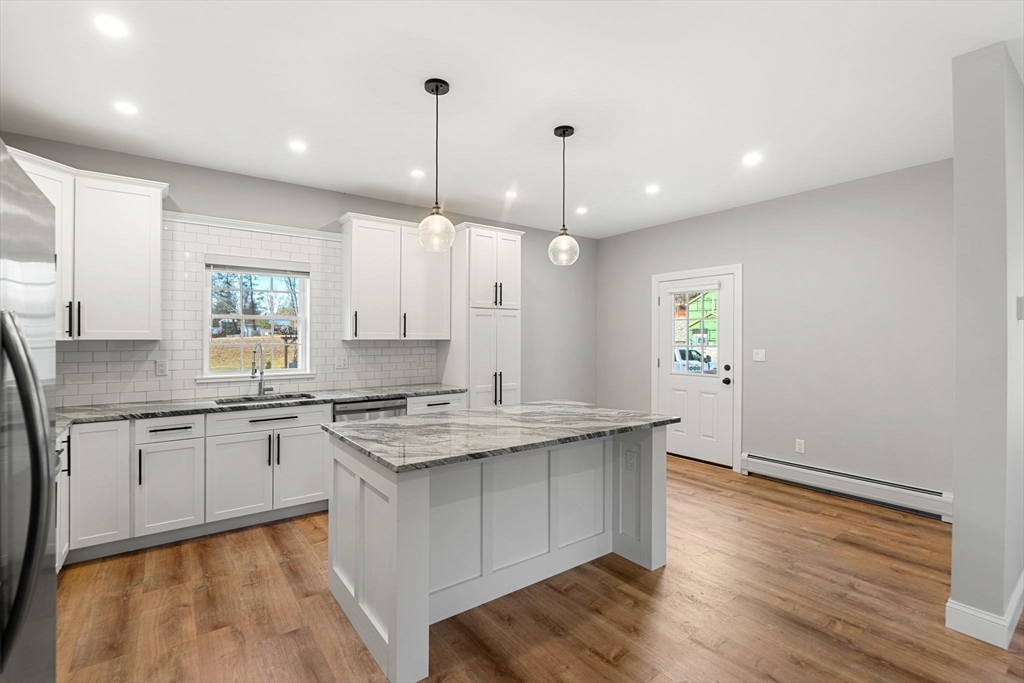249 Brookside Road Orange, MA 01364 - Photo 10 of 37 a large kitchen with stainless steel appliances granite countertop a sink a stove and a wooden floors