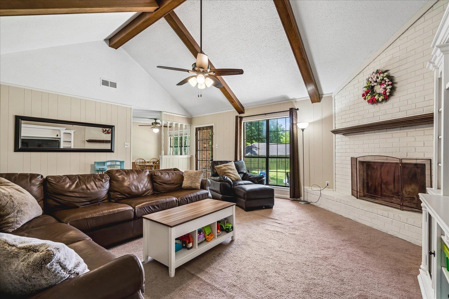 5711 Yale Road Bartlett, TN 38134 - Photo 3 of 29 Spacious living area featuring a vaulted ceiling with exposed wood beams, a brick fireplace with a wood mantle, and carpet flooring