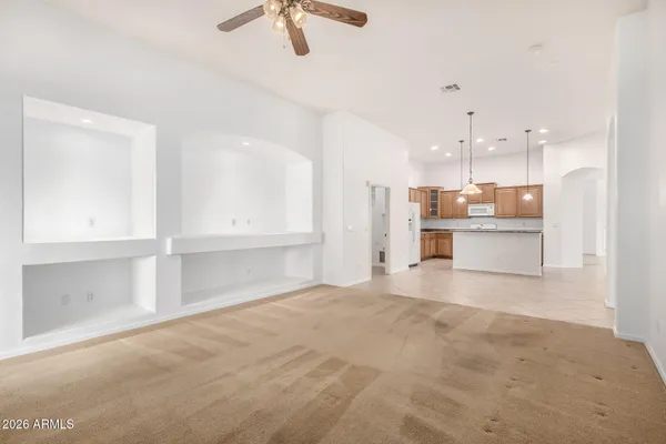 an empty room with chandelier fan and windows
