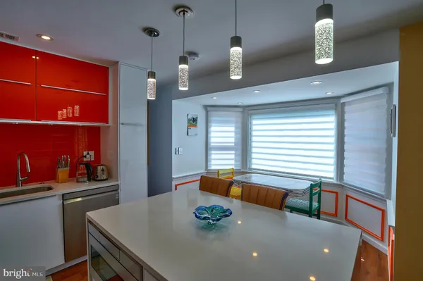 a kitchen with stainless steel appliances a dining table chairs refrigerator and sink