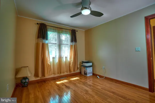 a view of empty room with wooden floor and fan