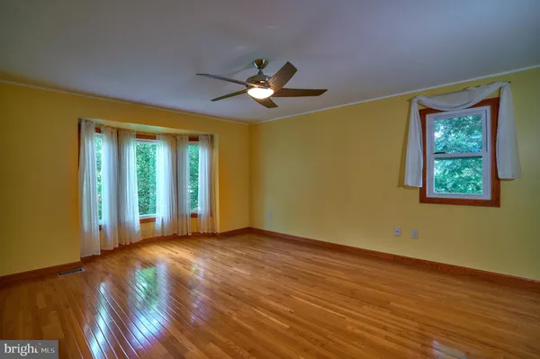 a view of empty room with wooden floor and fan
