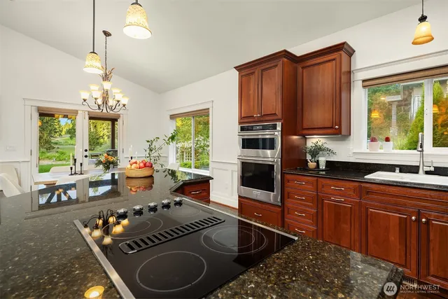 a kitchen with granite countertop a stove a sink and a refrigerator