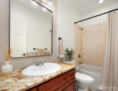 a bathroom with a granite countertop sink and a mirror with toilet