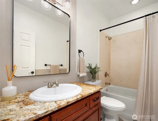 a bathroom with a granite countertop sink and a mirror with toilet
