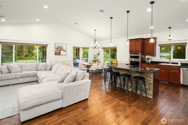 a living room with furniture kitchen area and a wooden floor