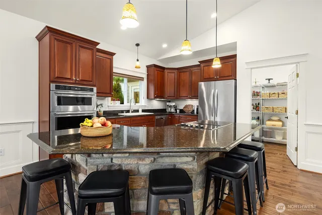 a kitchen with stainless steel appliances a dining table chairs refrigerator and sink