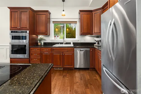 a kitchen with stainless steel appliances granite countertop a refrigerator a stove top oven and sink