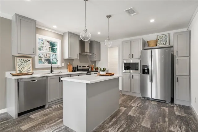 a kitchen with stainless steel appliances granite countertop a refrigerator a sink dishwasher a stove and white cabinets with wooden floor