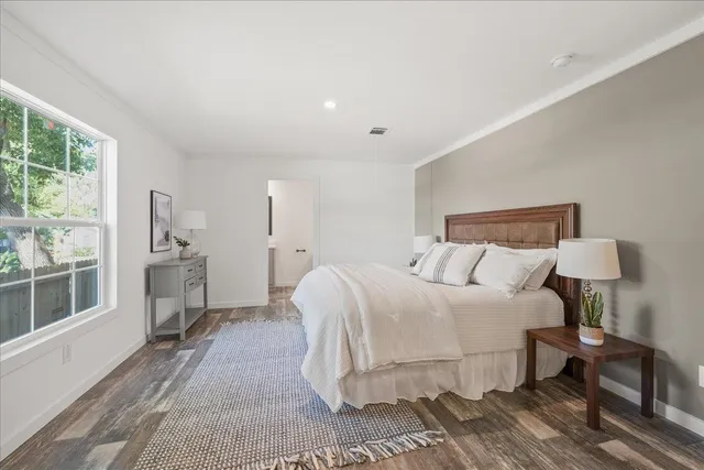 a bedroom with a large bed a chandelier and windows