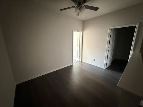 an empty room with wooden floor and fan