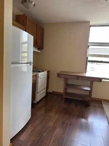 a kitchen with a refrigerator and a wooden floor