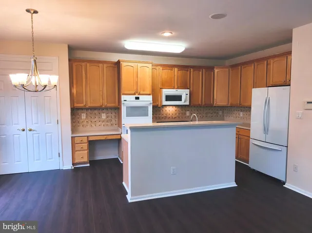 a kitchen with kitchen island granite countertop wooden floors white cabinets and stainless steel appliances
