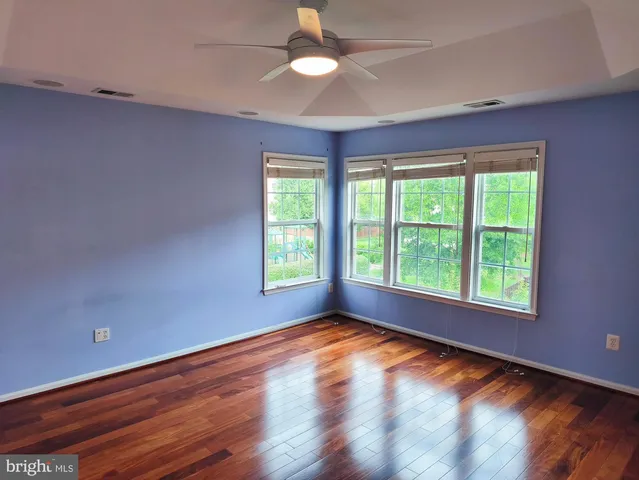 a view of empty room with wooden floor and fan