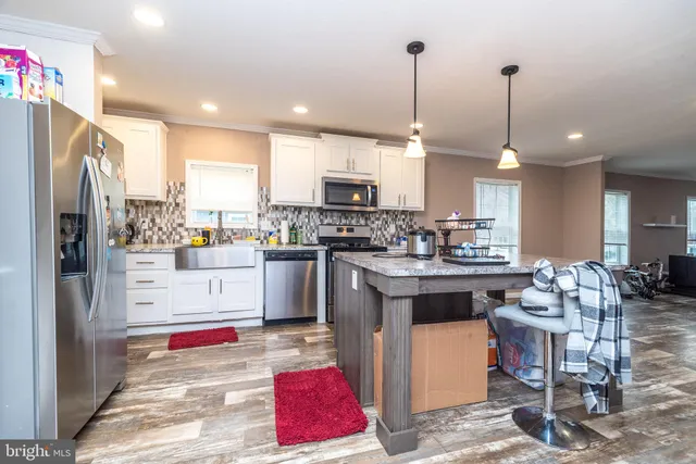 a kitchen with stainless steel appliances kitchen island granite countertop a refrigerator a stove top oven a sink and a chandelier