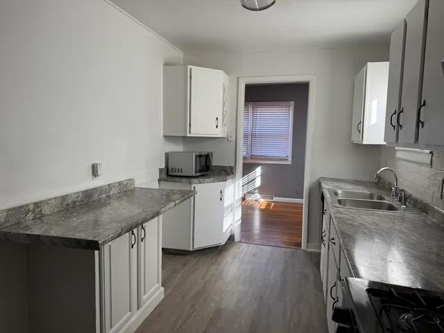 a kitchen with granite countertop a sink stove and cabinets