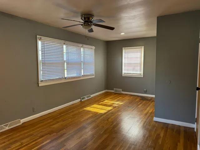 a view of a room with a ceiling fan and wooden floor
