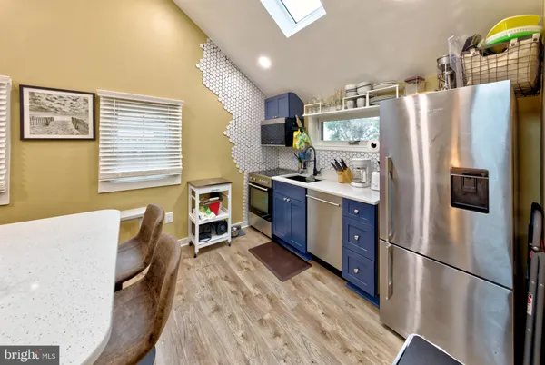a kitchen with stainless steel appliances a refrigerator a sink a stove a dining table and chairs