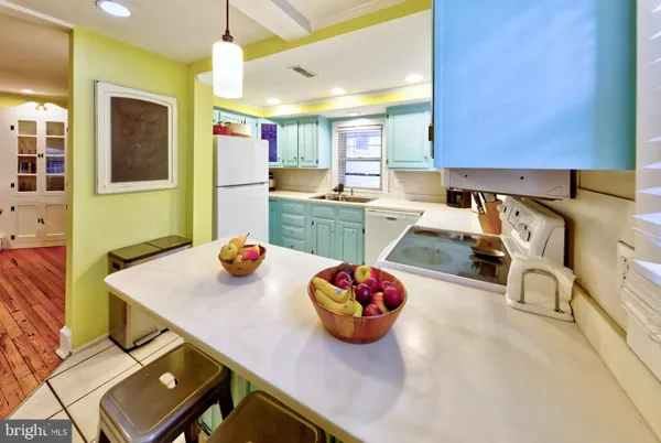 a kitchen with a sink a stove and chairs with wooden floor