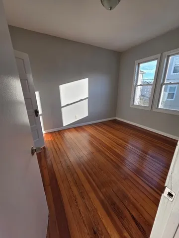 a view of empty room with window and wooden floor