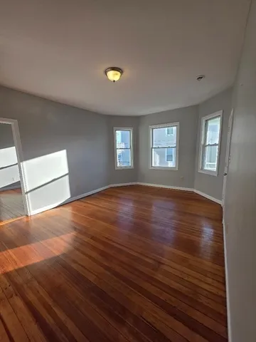 a view of empty room with window and wooden floor
