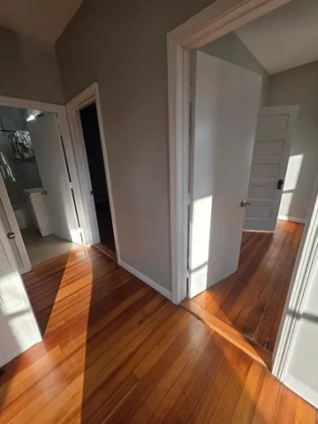 a view of an empty room with wooden floor and stairs