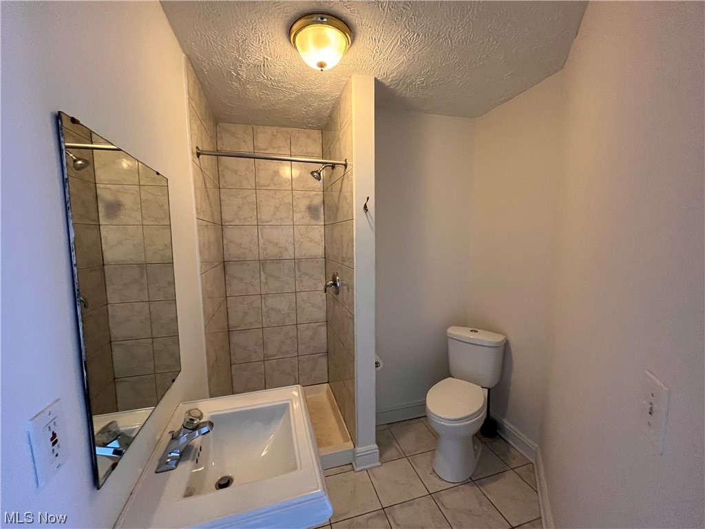 1697 Fulton Road Cleveland, OH 44113 - Photo 20 of 23 Bathroom featuring tile floors, a textured ceiling, tiled shower, and toilet