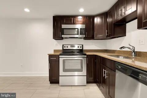 a kitchen with stainless steel appliances granite countertop a refrigerator a stove a sink and a microwave