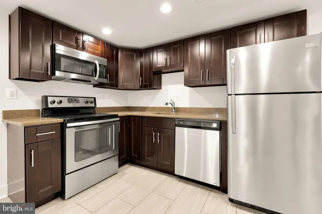 a kitchen with stainless steel appliances granite countertop a refrigerator a stove a sink and a microwave