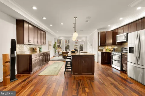 a kitchen with kitchen island wooden floors stainless steel appliances and cabinets
