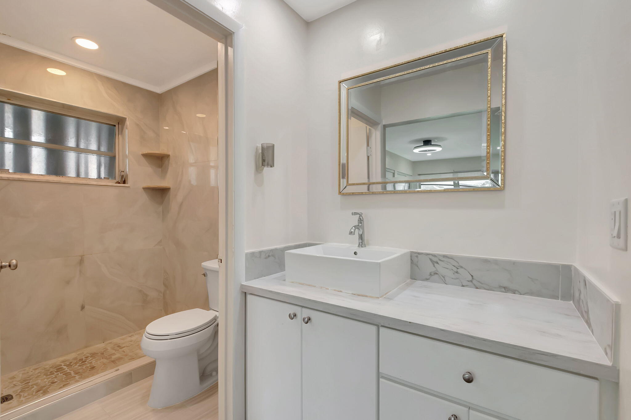1217 South Drive Way, Unit A Delray Beach, FL 33445 - Photo 24 of 27 a bathroom with a granite countertop sink a toilet and a mirror