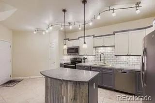 a kitchen with stainless steel appliances kitchen island granite countertop a sink a counter space cabinets and wooden floor